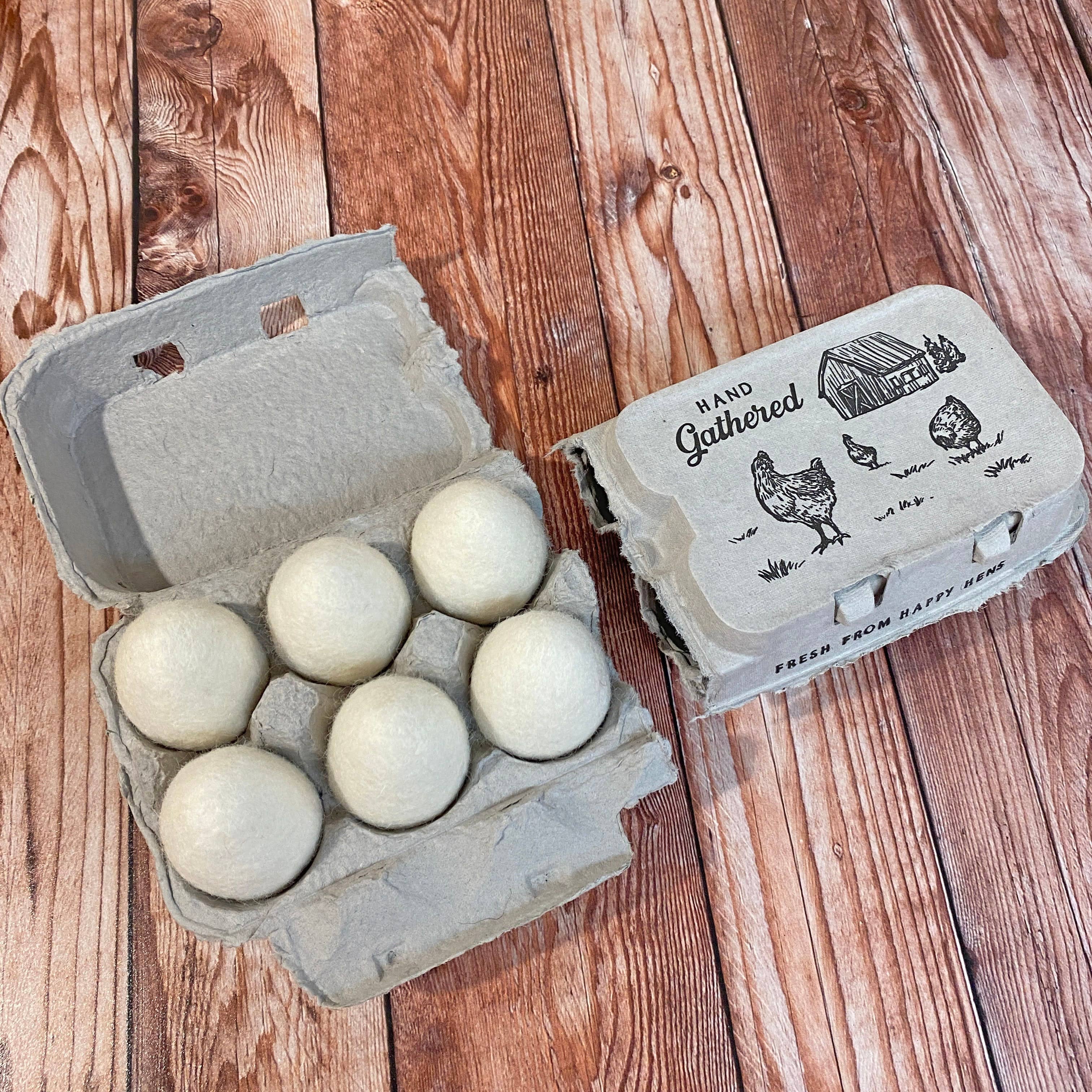 Carton of wool felt eggs on a wooden surface with a rustic design.