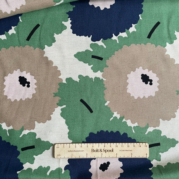Fabric with a floral pattern featuring green, blue, and beige colors, with a ruler for scale.