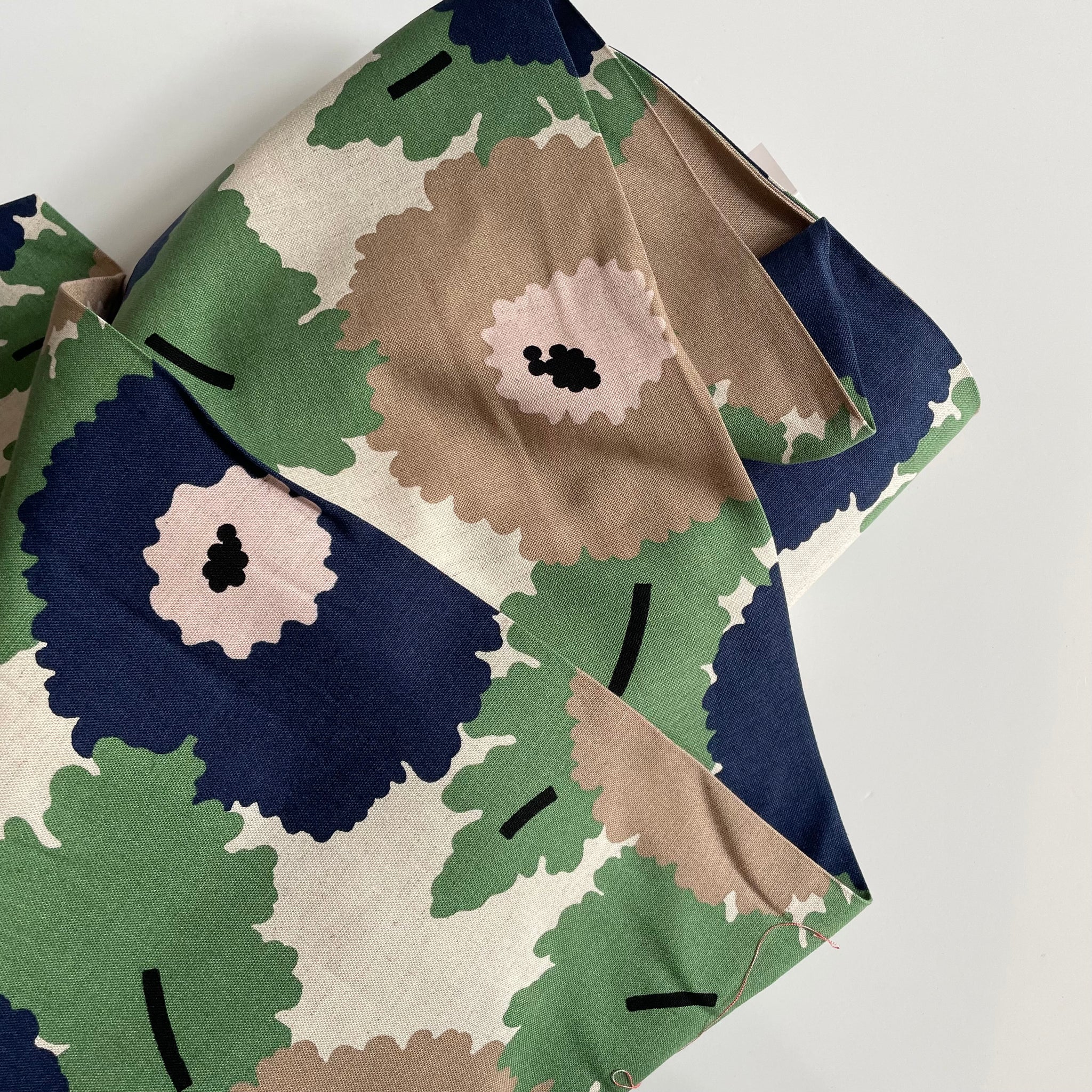 Camouflage-patterned fabric with green, brown, and blue colors on a white background